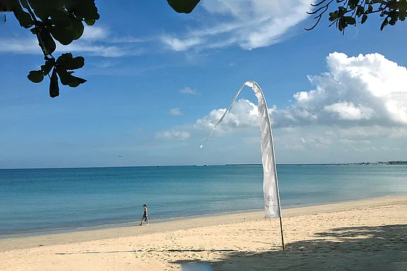 Frau unternimmt gemütlichen Strandspaziergang am Sandstrand von Jimbaran auf Bali